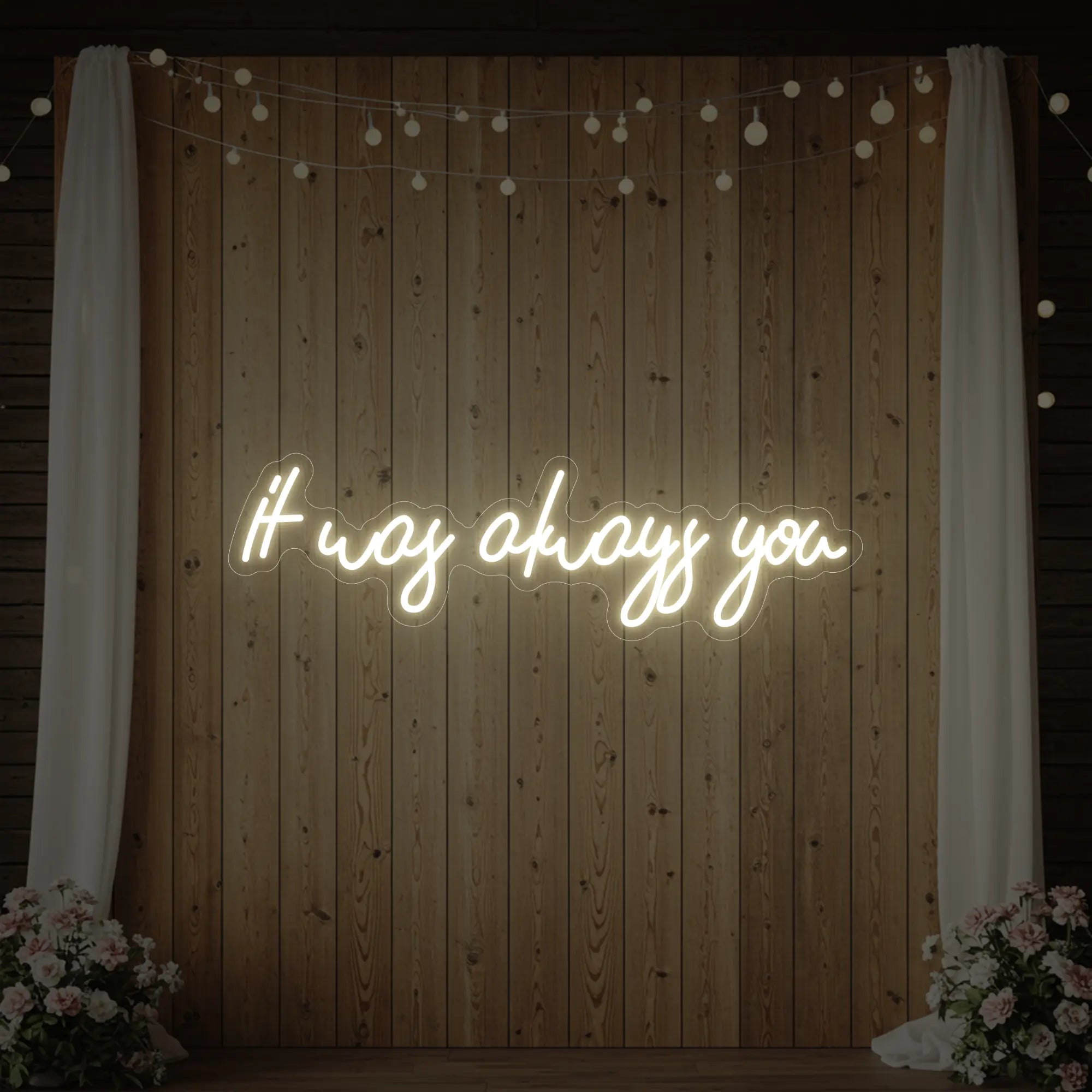 Photo of the 'It Was Always You' neon sign glowing in warm white against a styled interior wall.