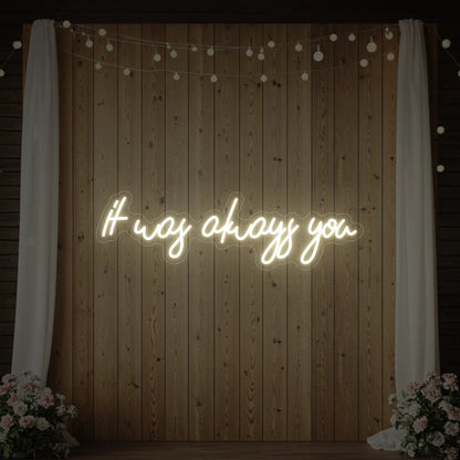 Photo of the 'It Was Always You' neon sign glowing in warm white against a styled interior wall.