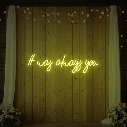 Photo of the 'It Was Always You' neon sign glowing in lemon yellow against a styled interior wall.