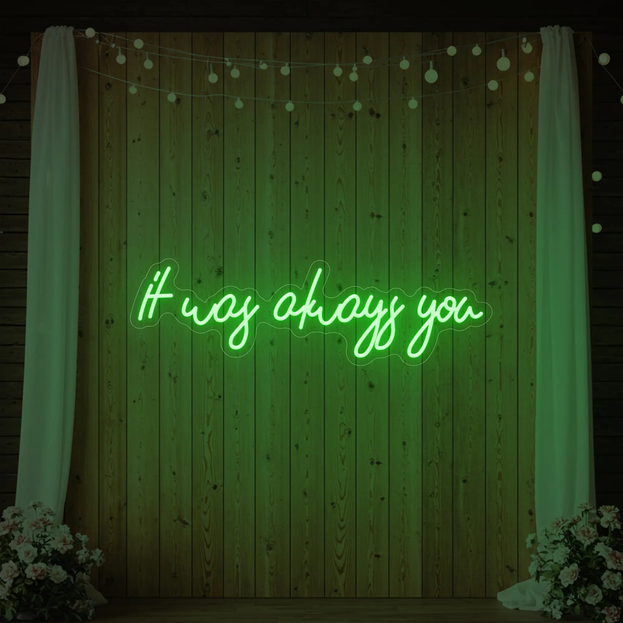 Photo of the 'It Was Always You' neon sign glowing in green against a styled interior wall.