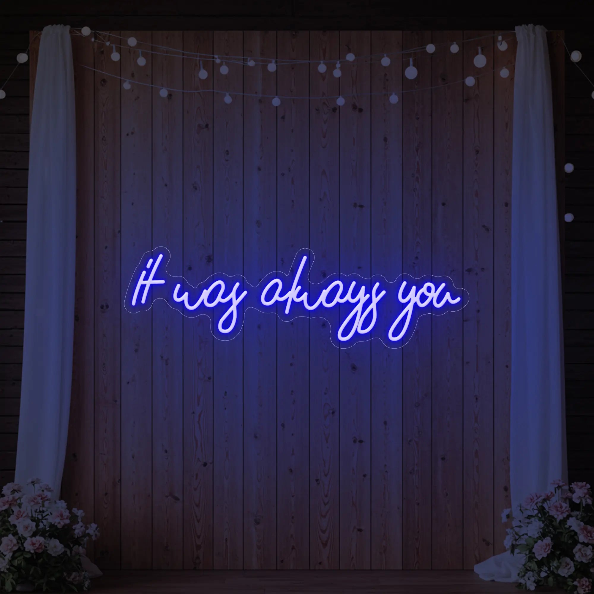 Photo of the 'It Was Always You' neon sign glowing in deep blue against a styled interior wall.