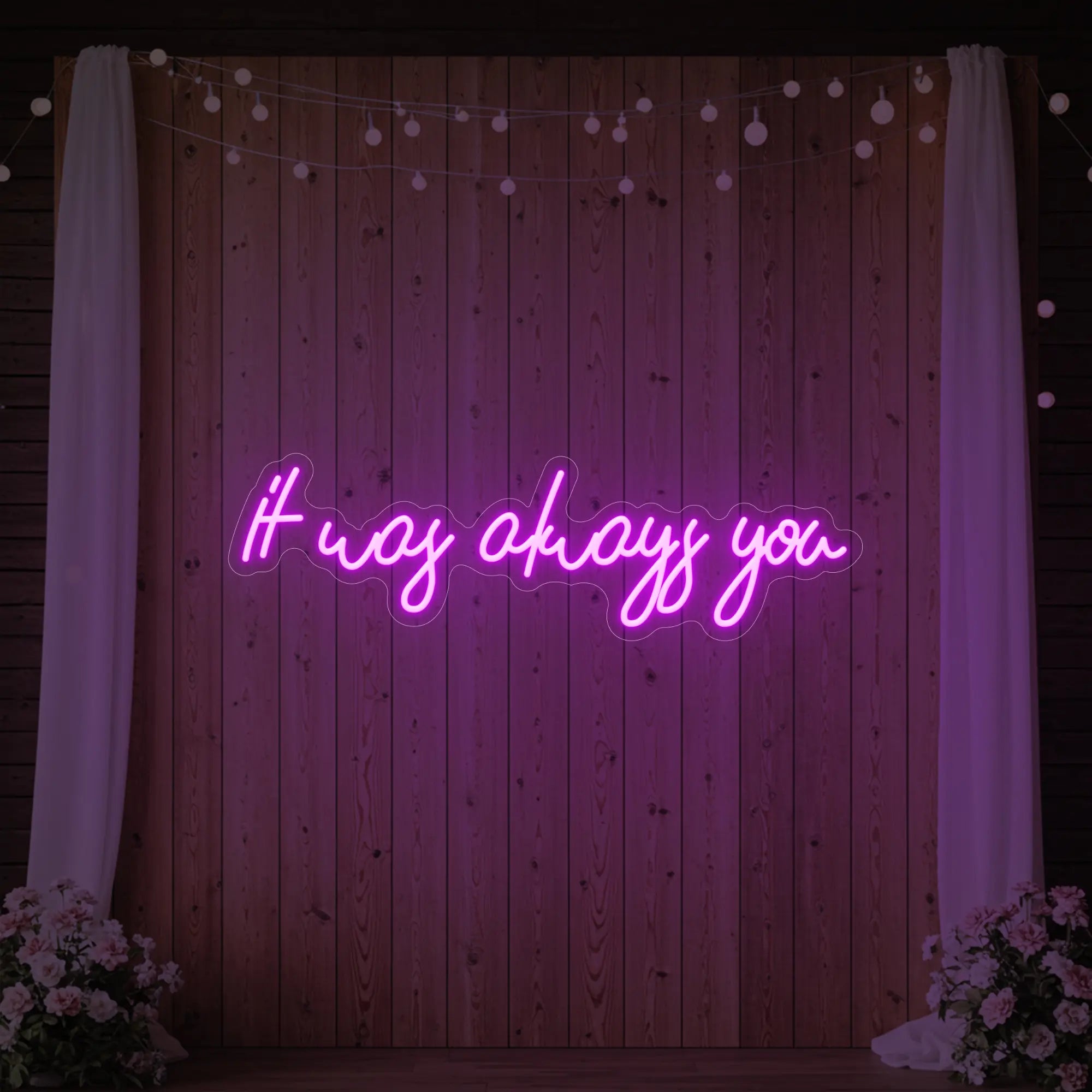 Photo of the 'It Was Always You' neon sign glowing in deep pink against a styled interior wall.