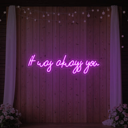 Photo of the 'It Was Always You' neon sign glowing in deep pink against a styled interior wall.