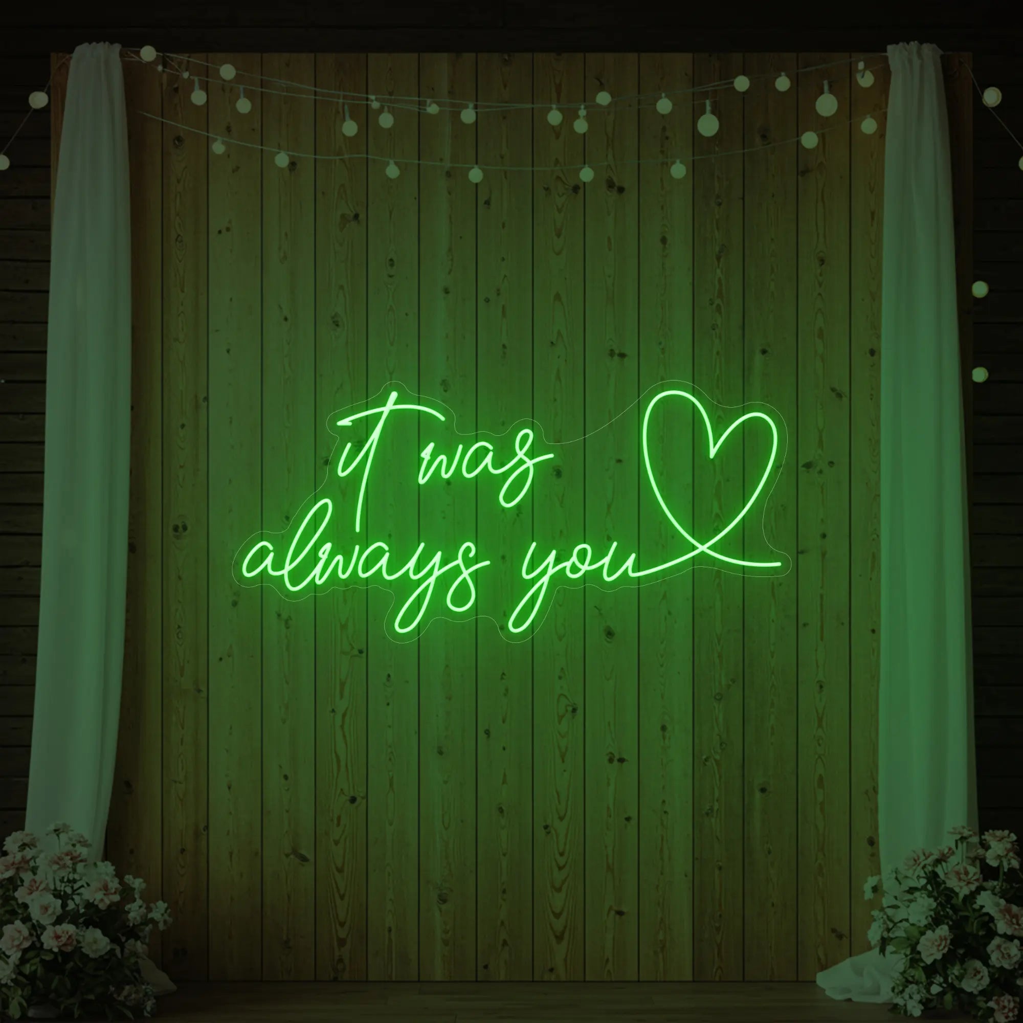Photo of the 'It Was Always You Heart' neon sign glowing in green against a styled interior wall.