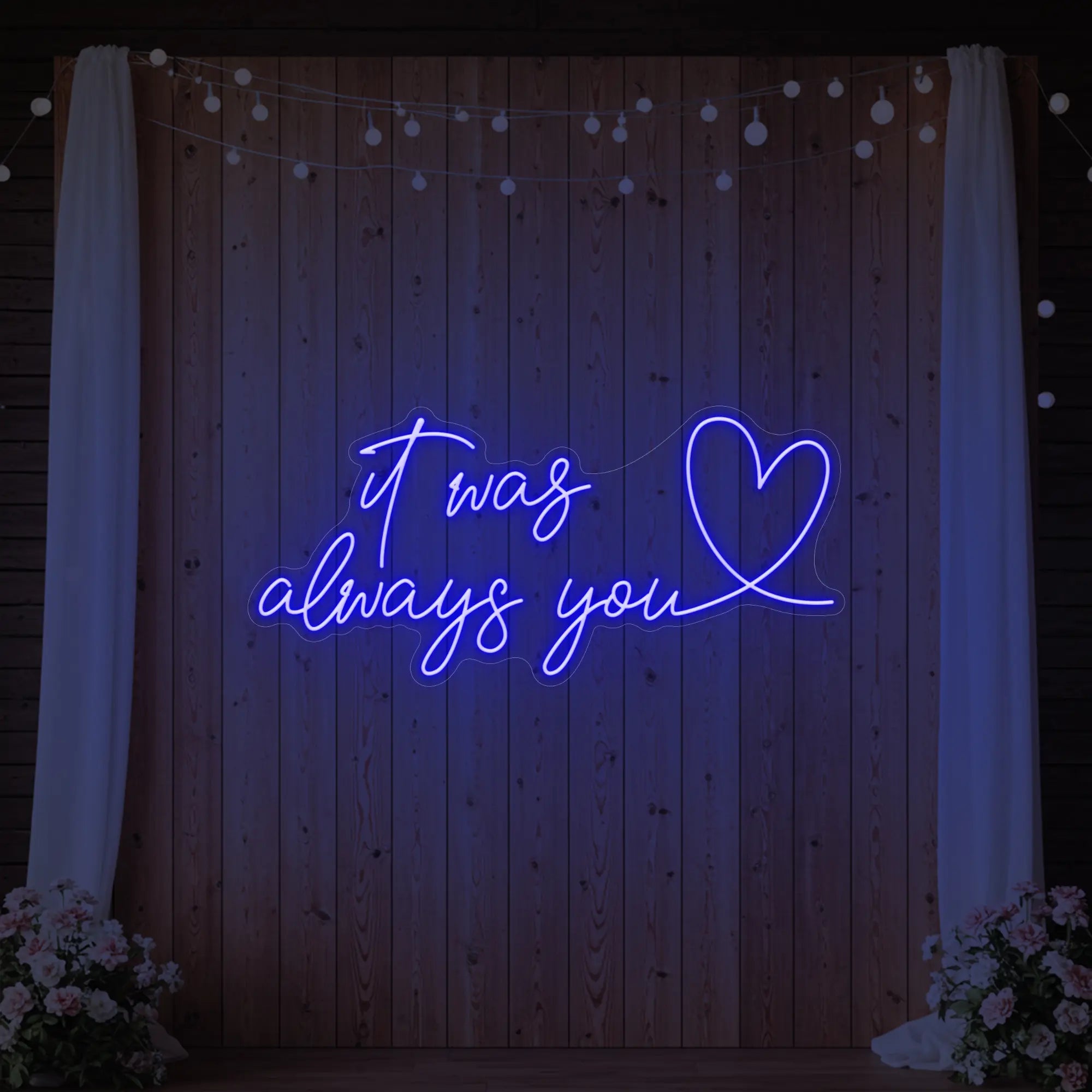 Photo of the 'It Was Always You Heart' neon sign glowing in deep blue against a styled interior wall.
