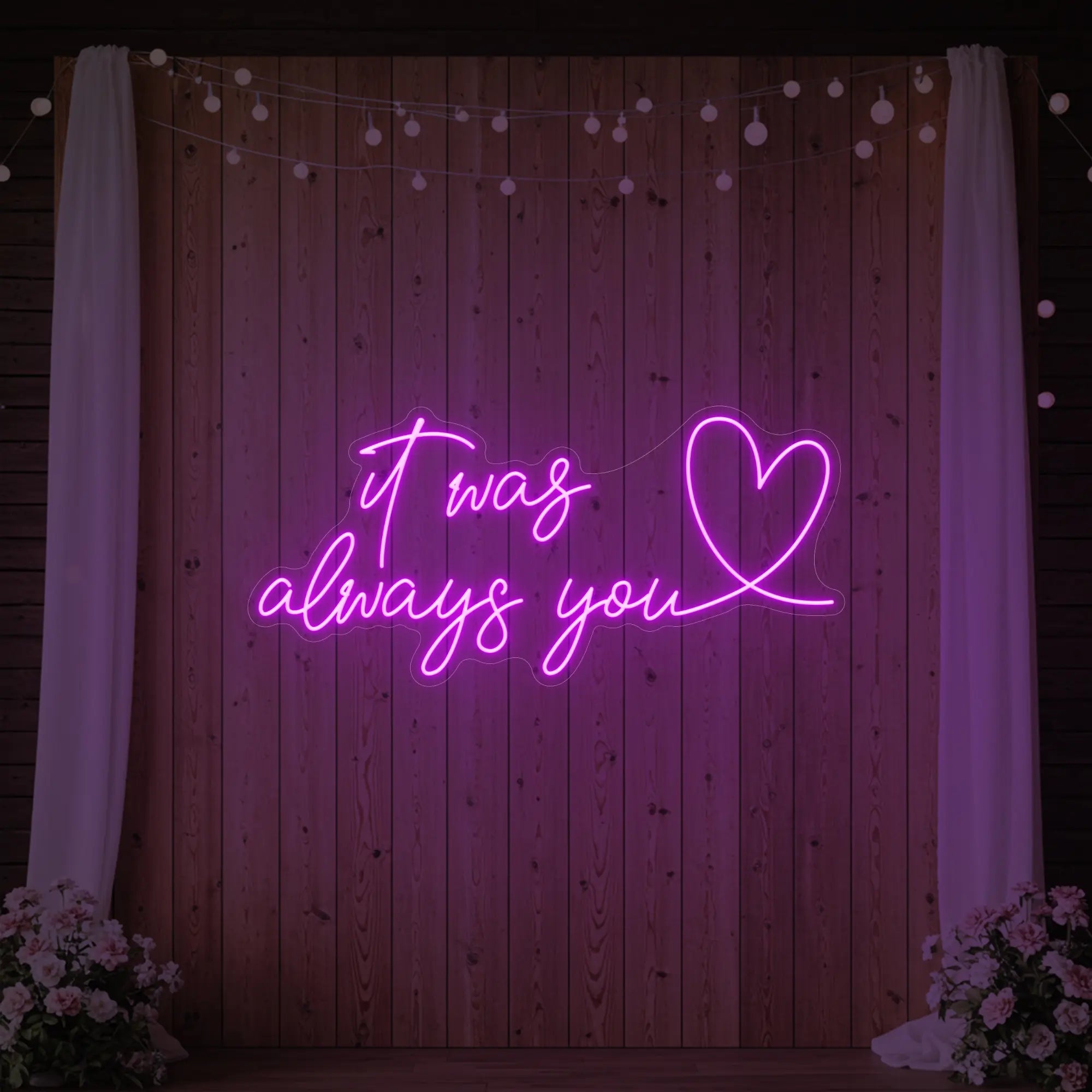 Photo of the 'It Was Always You Heart' neon sign glowing in deep pink against a styled interior wall.
