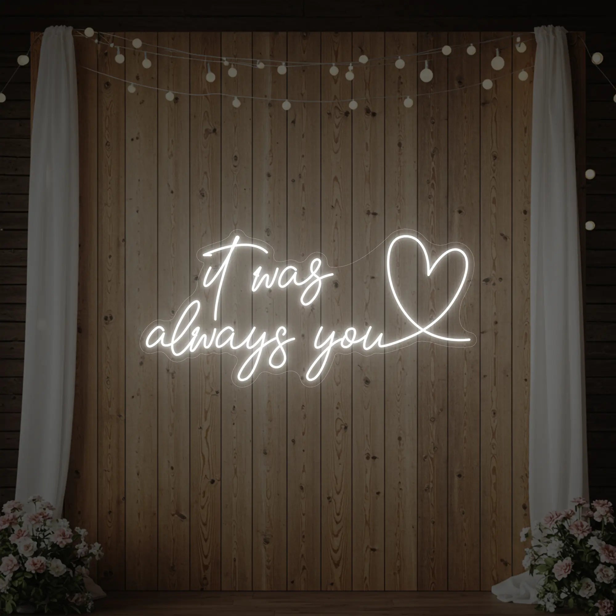 Photo of the 'It Was Always You Heart' neon sign glowing in cool white against a styled interior wall.
