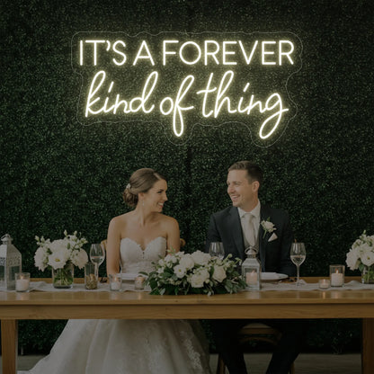 Photo of the 'It’s a Forever Kind of Thing' neon sign glowing in warm white against a styled interior wall.