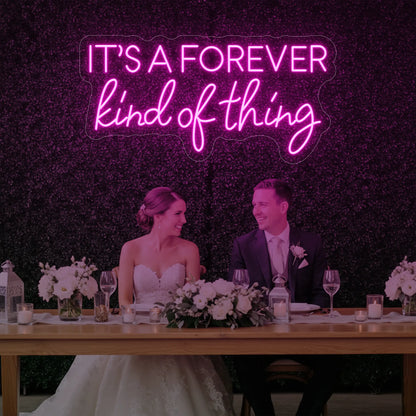 Photo of the 'It’s a Forever Kind of Thing' neon sign glowing in light pink against a styled interior wall.