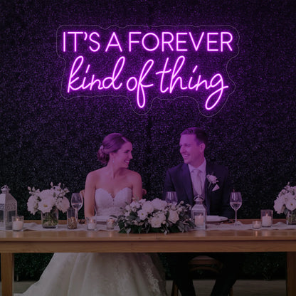 Photo of the 'It’s a Forever Kind of Thing' neon sign glowing in deep pink against a styled interior wall.