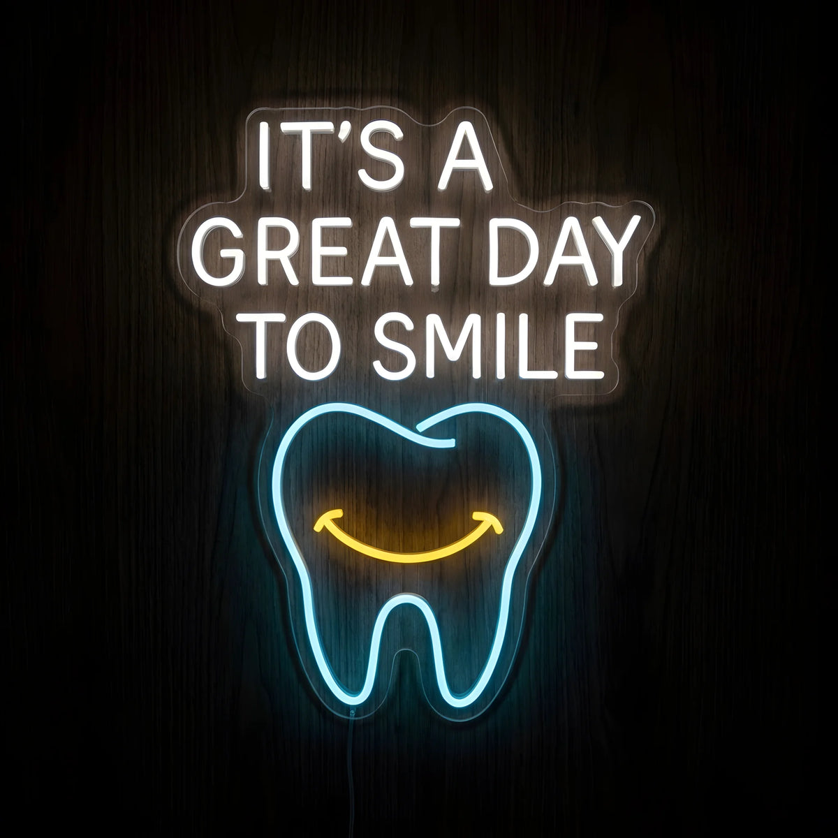 It's a Great Day to Smile LED neon sign featuring glowing white motivational lettering above a blue tooth outline with a yellow smiling face on clear acrylic backing against a dark wooden wall.