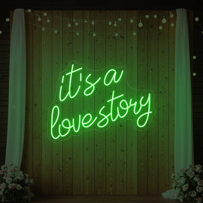 Photo of the 'It’s a Love Story' neon sign glowing in green against a styled interior wall.