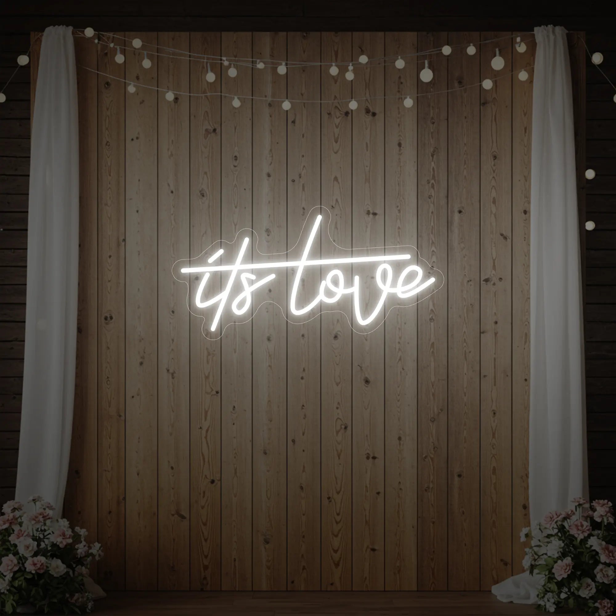 Photo of the 'It’s Love' neon sign glowing in cool white against a styled interior wall.