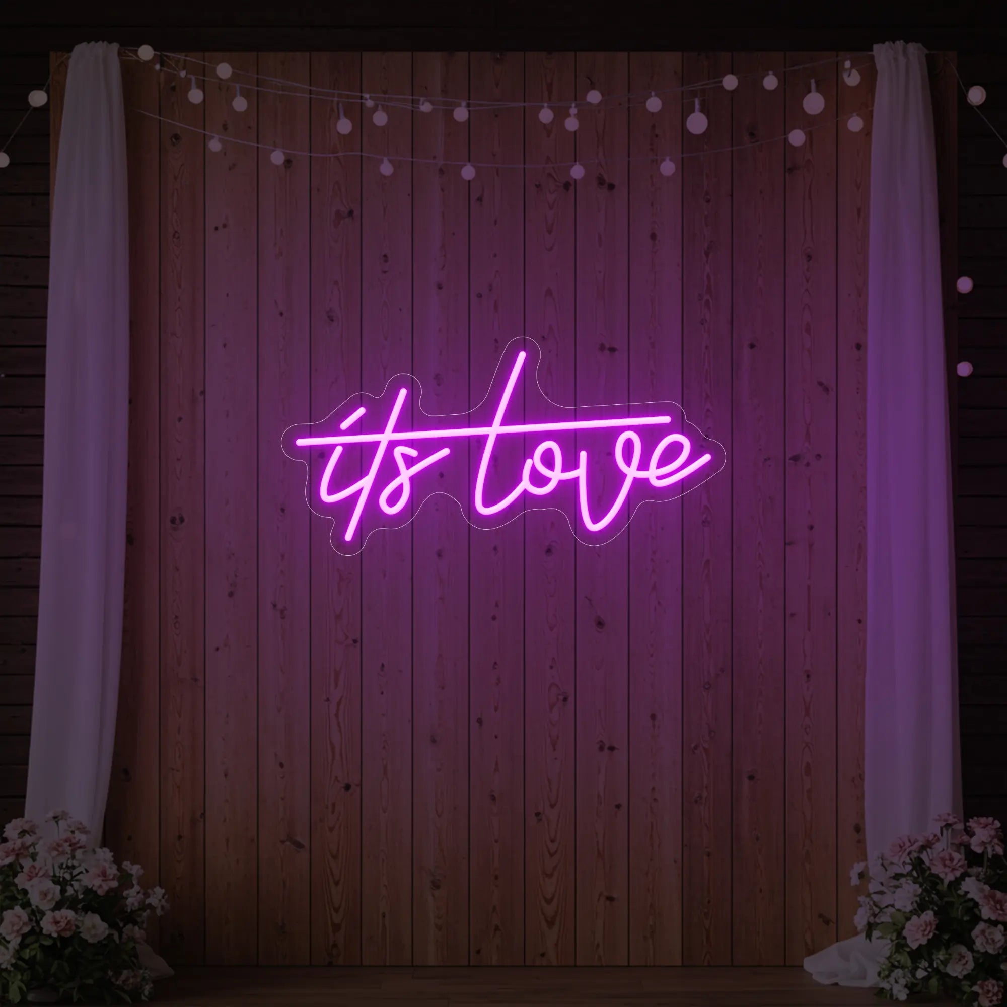 Photo of the 'It’s Love' neon sign glowing in deep pink against a styled interior wall.
