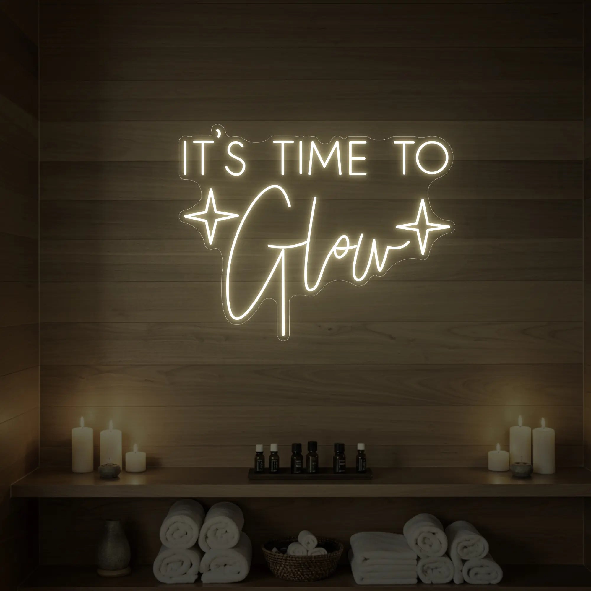 Photo of the 'IT’S TIME TO Glow' neon sign with sparkle icons glowing in warm white against a styled interior wall.