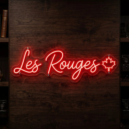 Les Rouges LED neon sign in bright red script lettering with maple leaf accent mounted on clear acrylic backing