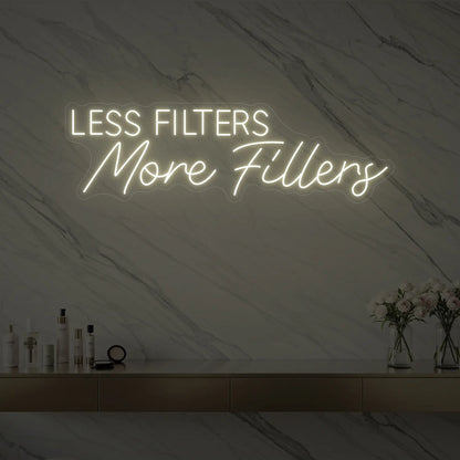 Photo of the 'LESS FILTERS MORE FILLERS' neon sign glowing in warm white against a marble wall.
