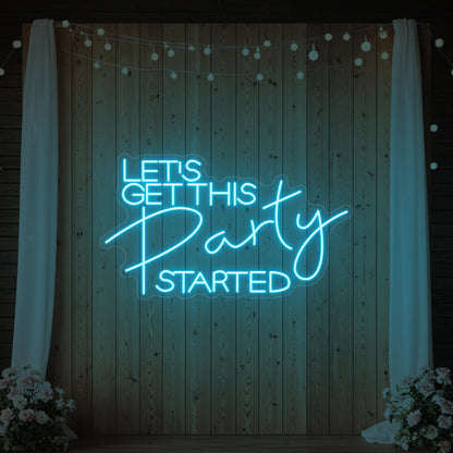 Photo of the 'Let’s Get This Party Started' neon sign glowing in ice blue against a styled interior wall.