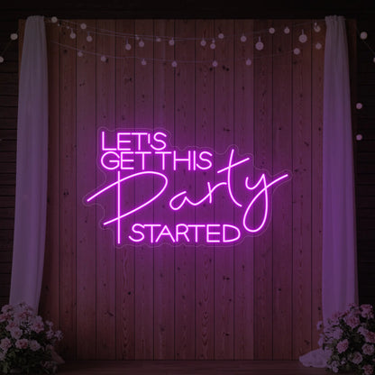 Photo of the 'Let’s Get This Party Started' neon sign glowing in deep pink against a styled interior wall.