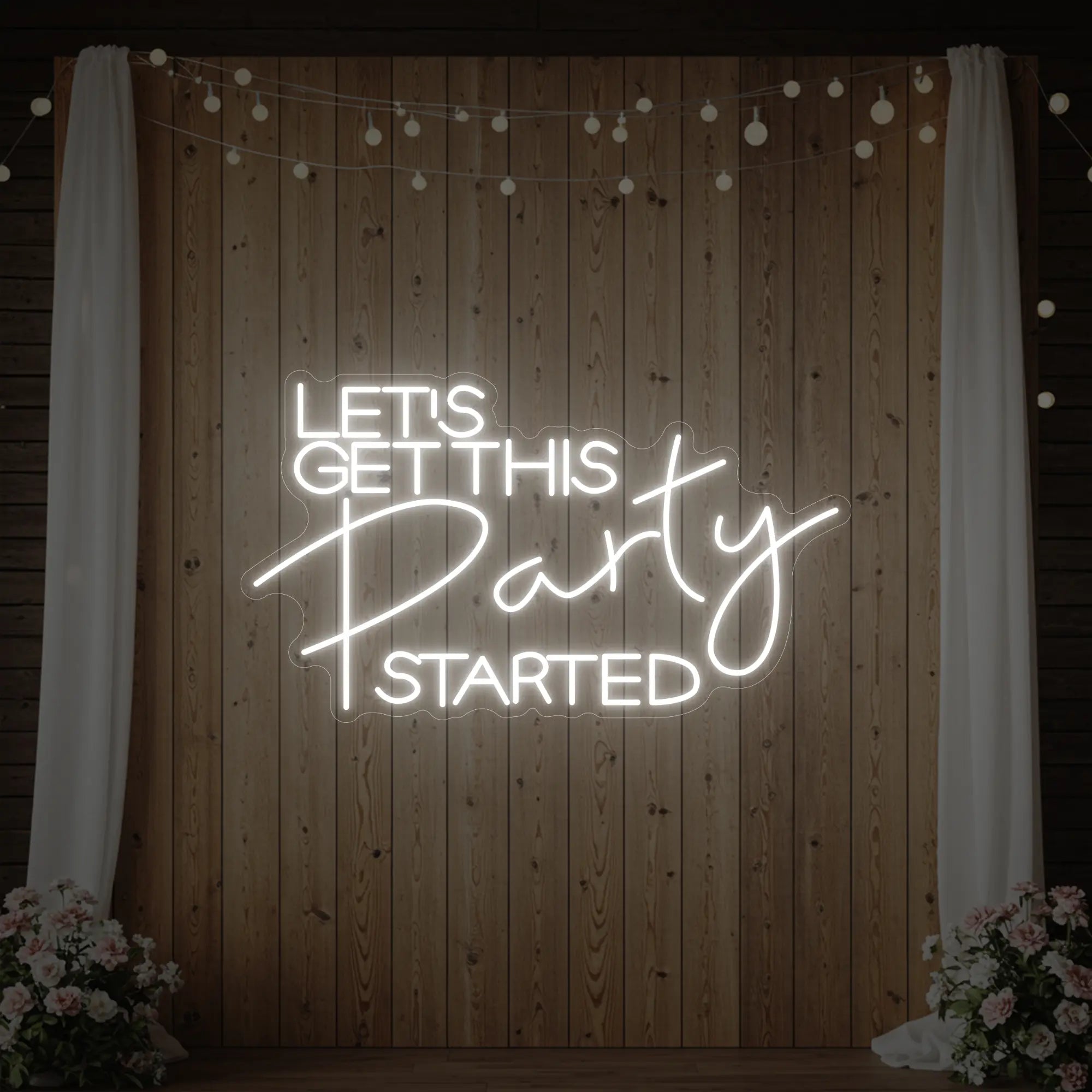 Photo of the 'Let’s Get This Party Started' neon sign glowing in cool white against a styled interior wall.