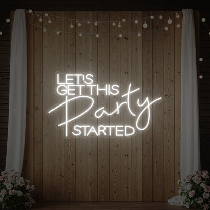 Photo of the 'Let’s Get This Party Started' neon sign glowing in cool white against a styled interior wall.