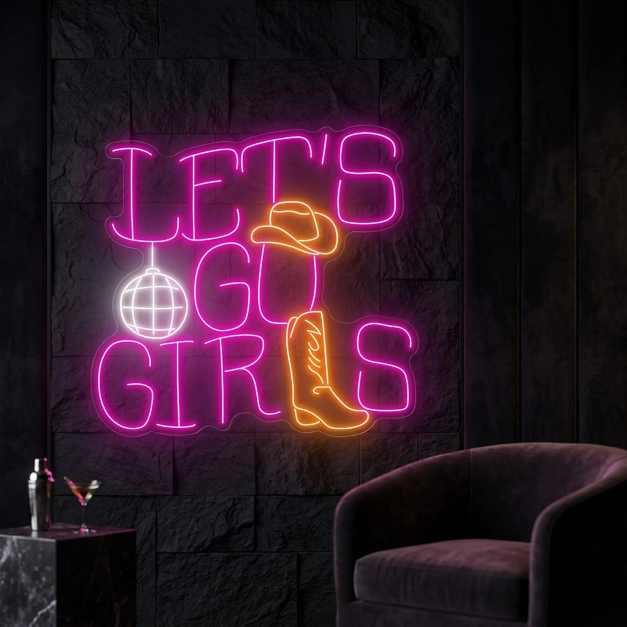 Photo of the 'Let's Go Girls' neon sign glowing in multi-color against a styled interior wall.