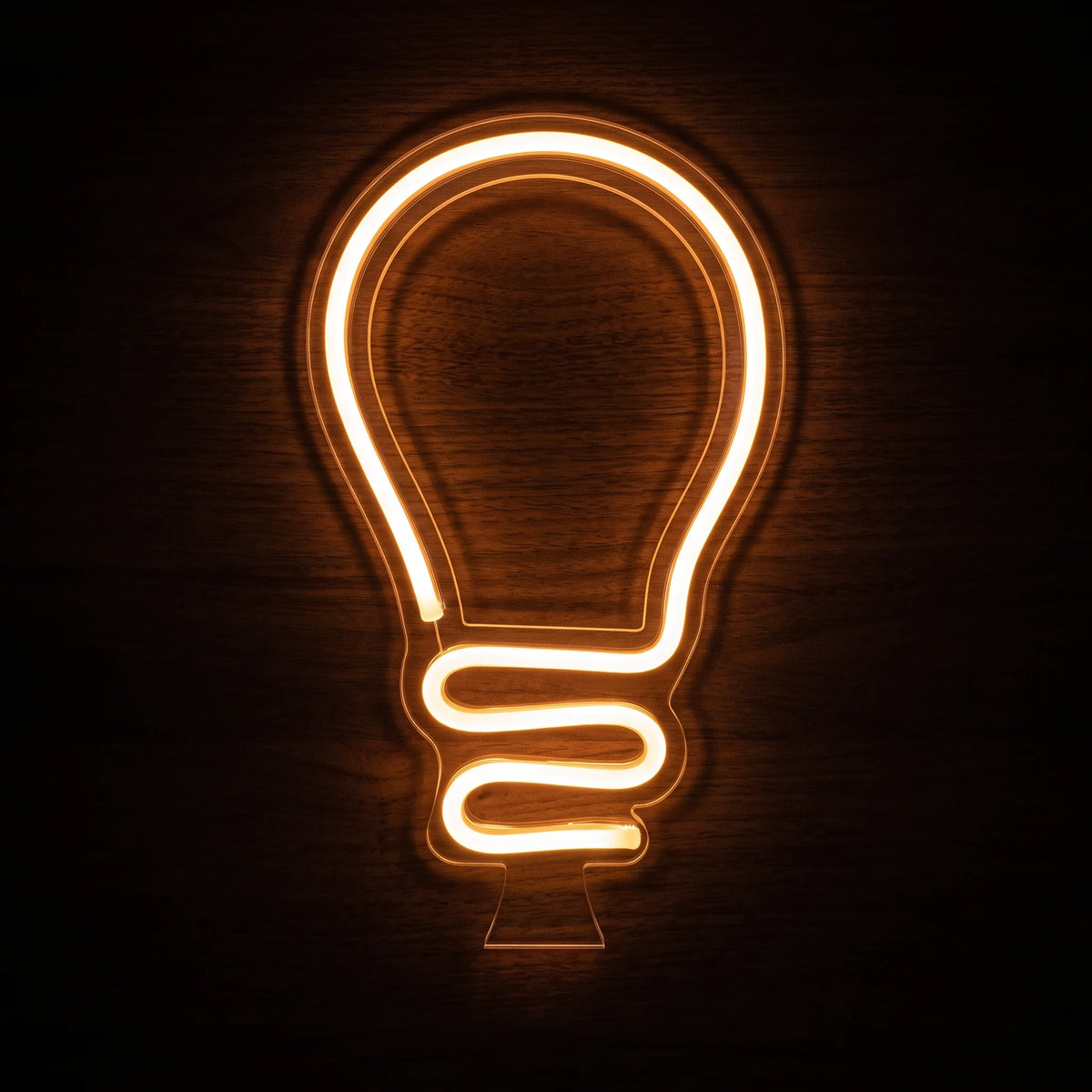 Light Bulb LED Neon Sign with warm glowing bulb outline on clear cut-to-shape acrylic backing.