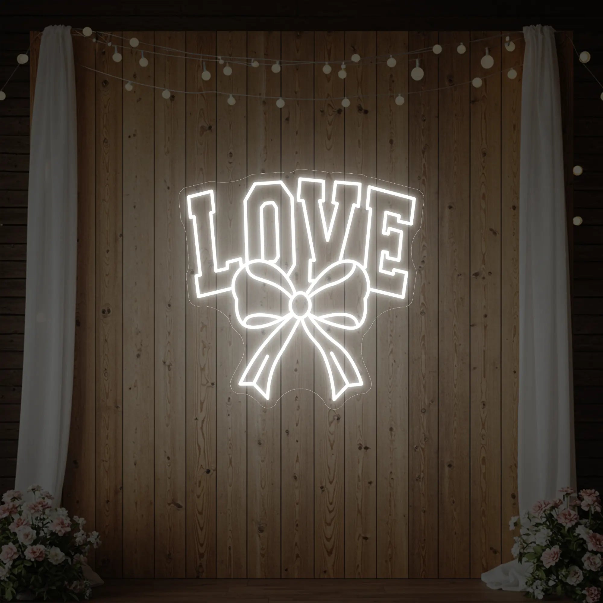 Photo of the 'Love and Ribbon' neon sign glowing in cool white against a styled interior wall.