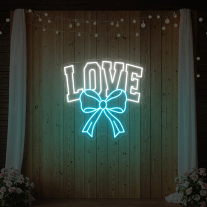 Photo of the 'Love and Ribbon' neon sign glowing in ice blue against a styled interior wall.
