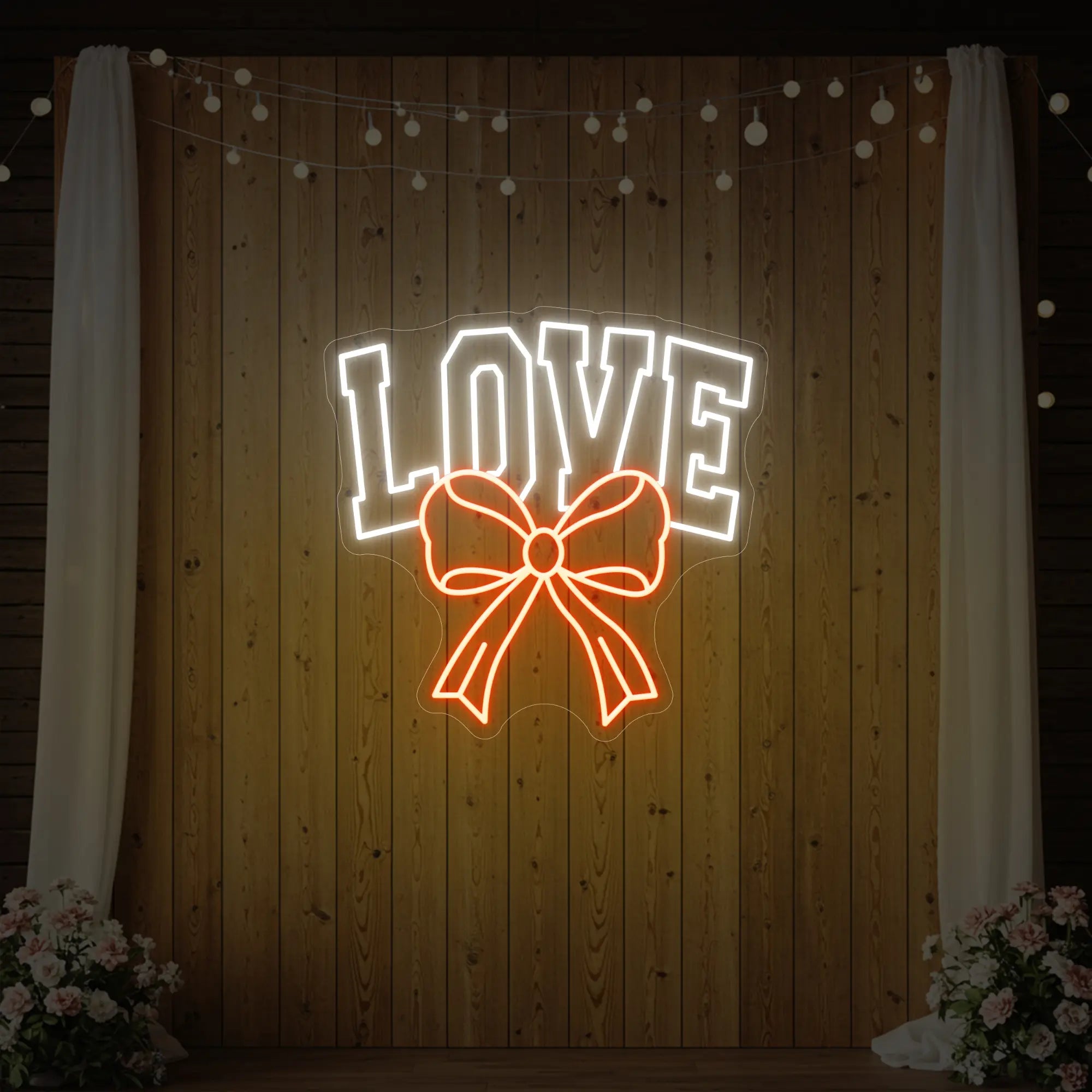 Photo of the 'Love and Ribbon' neon sign glowing in golden yellow against a styled interior wall.