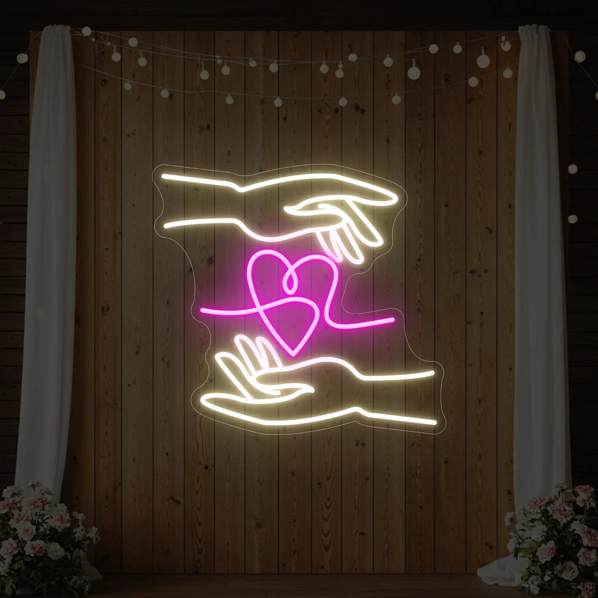 Photo of the 'Love Hands' neon sign glowing in light pink and cool white against a styled interior wall.