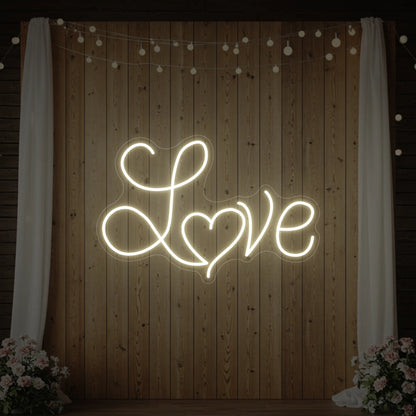 Photo of the 'Love Heart' neon sign glowing in warm white against a styled background.