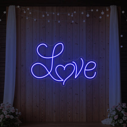 Photo of the 'Love Heart' neon sign glowing in deep blue against a styled interior wall.