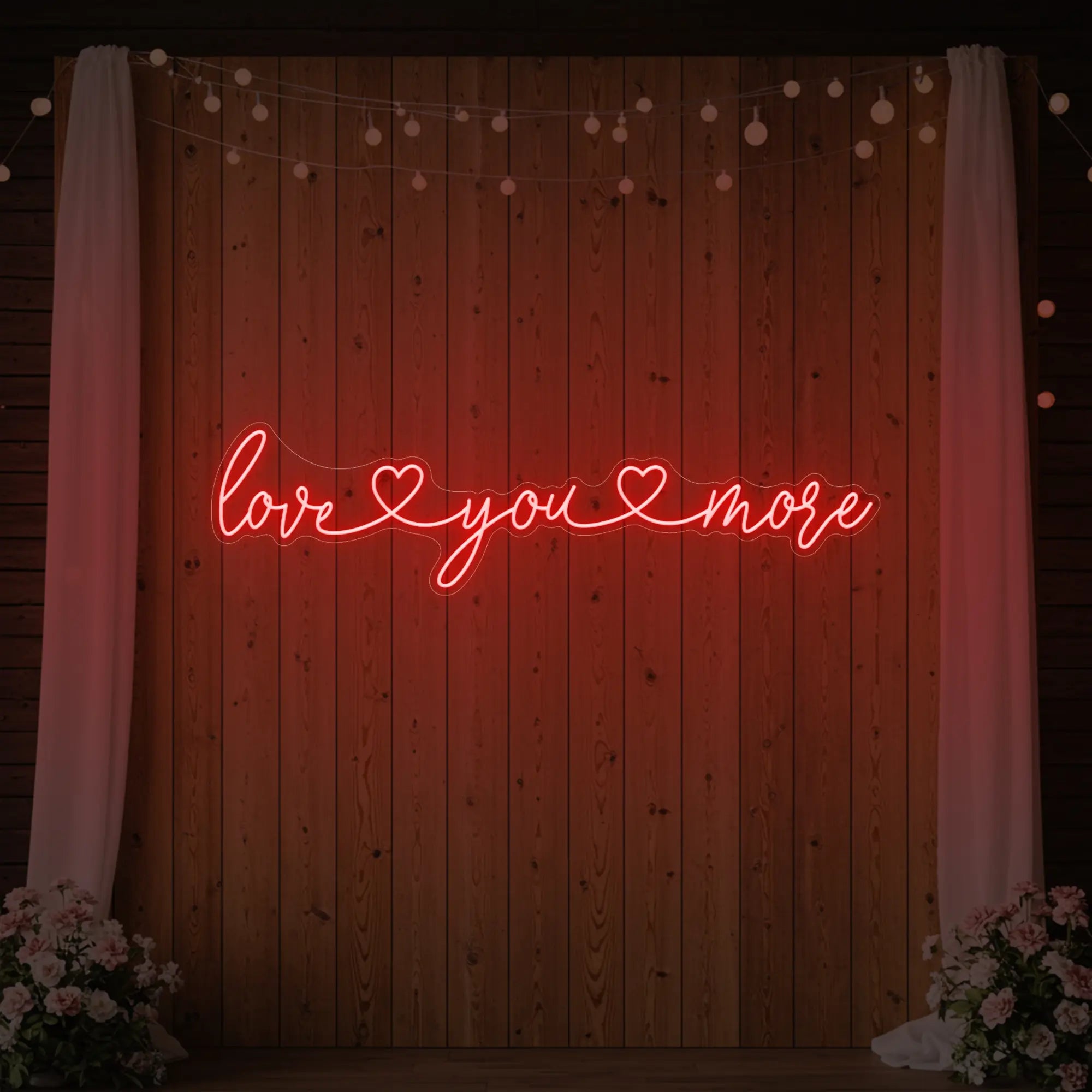 Photo of the 'Love You More' neon sign glowing in red against a styled interior wall.
