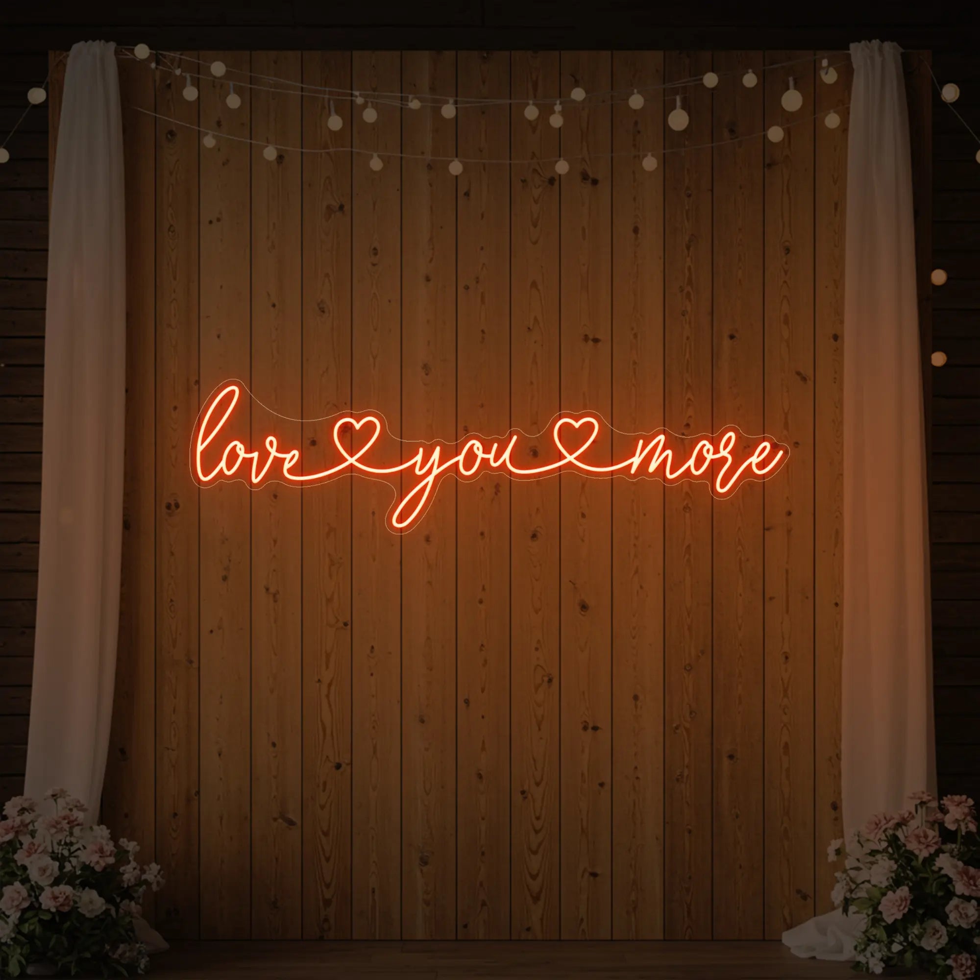 Photo of the 'Love You More' neon sign glowing in golden yellow against a styled interior wall.