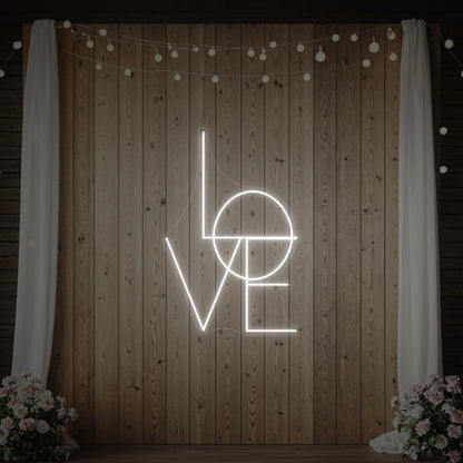 Photo of the 'LOVE' neon sign glowing in cool white against a styled interior wall.
