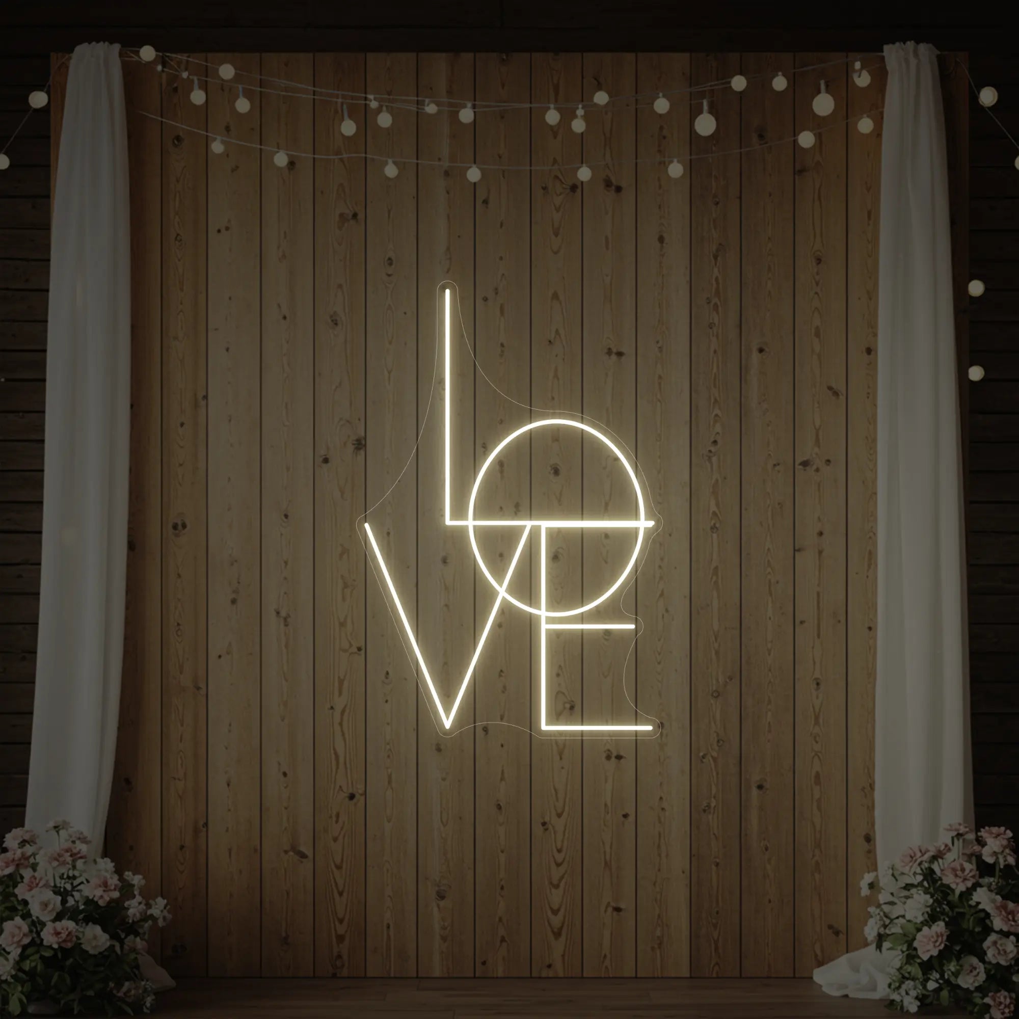 Photo of the 'LOVE' neon sign glowing in warm white against a styled interior wall.