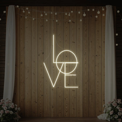 Photo of the 'LOVE' neon sign glowing in warm white against a styled interior wall.