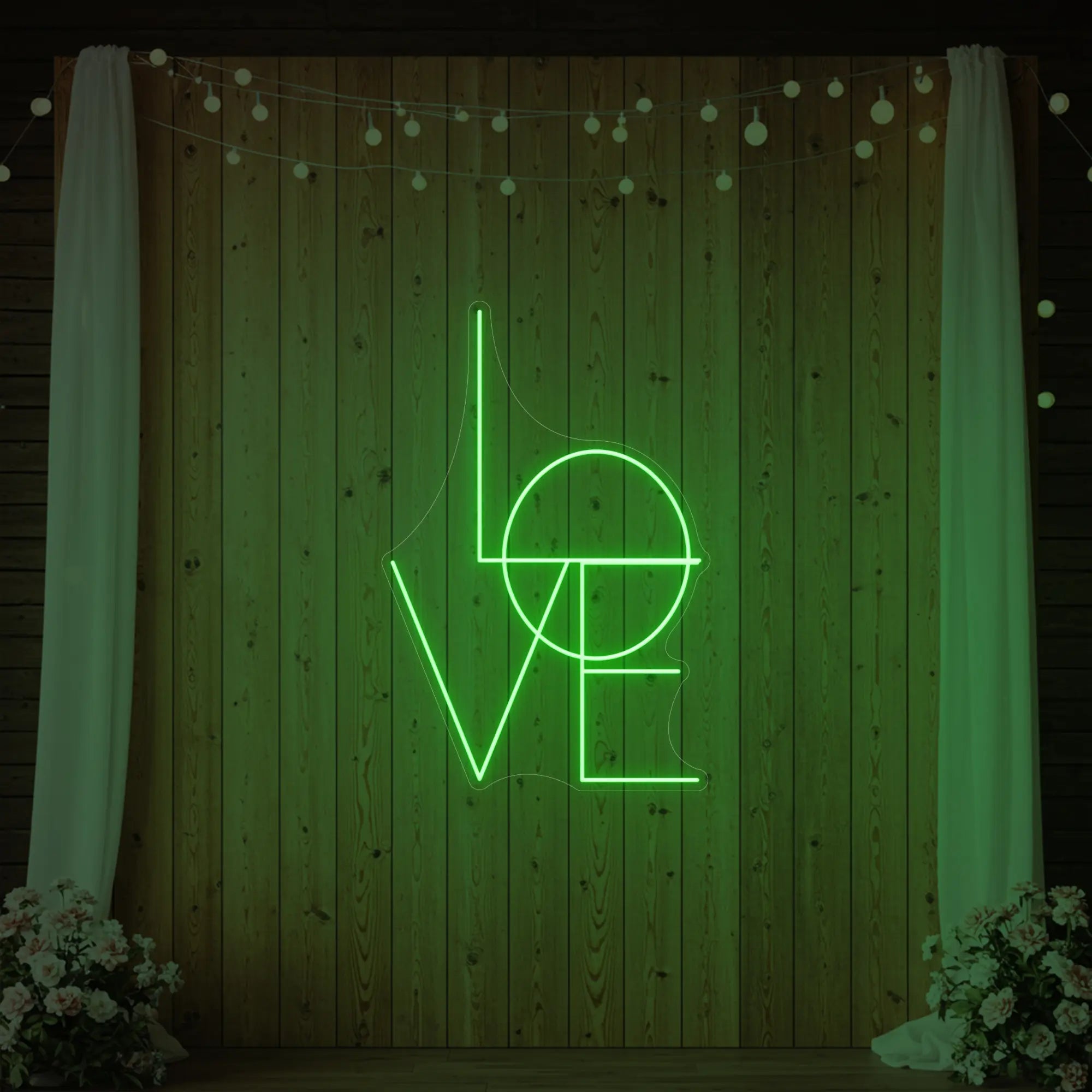 Photo of the 'LOVE' neon sign glowing in green against a styled interior wall.