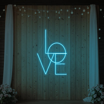 Photo of the 'LOVE' neon sign glowing in ice blue against a styled interior wall.