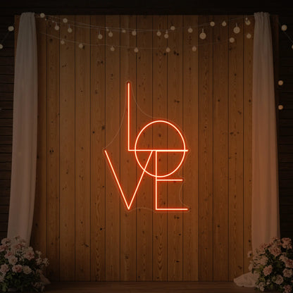 Photo of the 'LOVE' neon sign glowing in golden yellow against a styled interior wall.