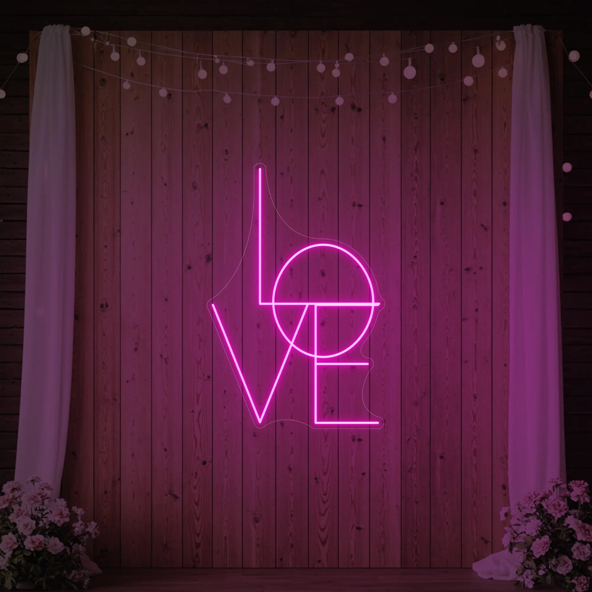 Photo of the 'LOVE' neon sign glowing in light pink against a styled interior wall.