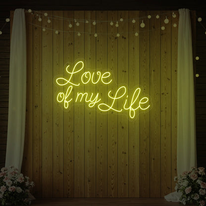 Photo of the 'Love of My Life' neon sign glowing in lemon yellow against a styled interior wall.