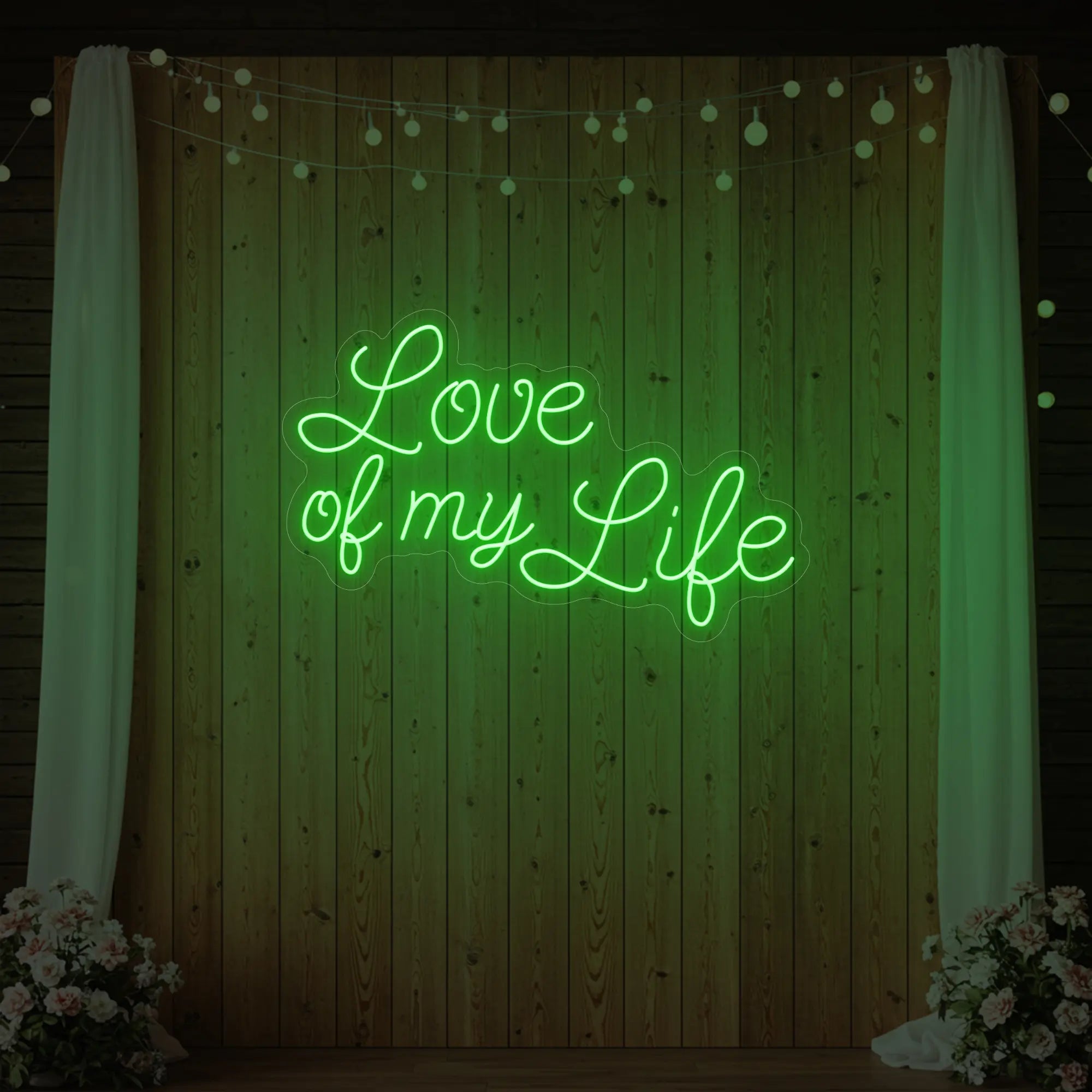 Photo of the 'Love of My Life' neon sign glowing in green against a styled interior wall.