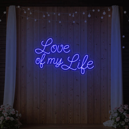 Photo of the 'Love of My Life' neon sign glowing in deep blue against a styled interior wall.
