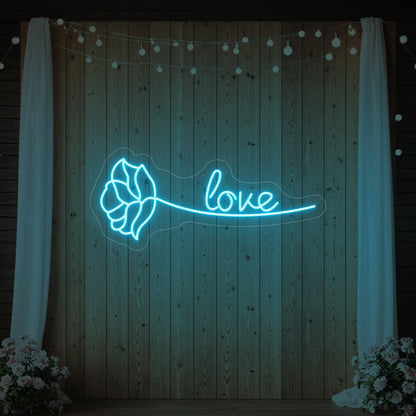 Photo of the 'Just Love Rose' neon sign glowing in ice blue against a styled interior wall.