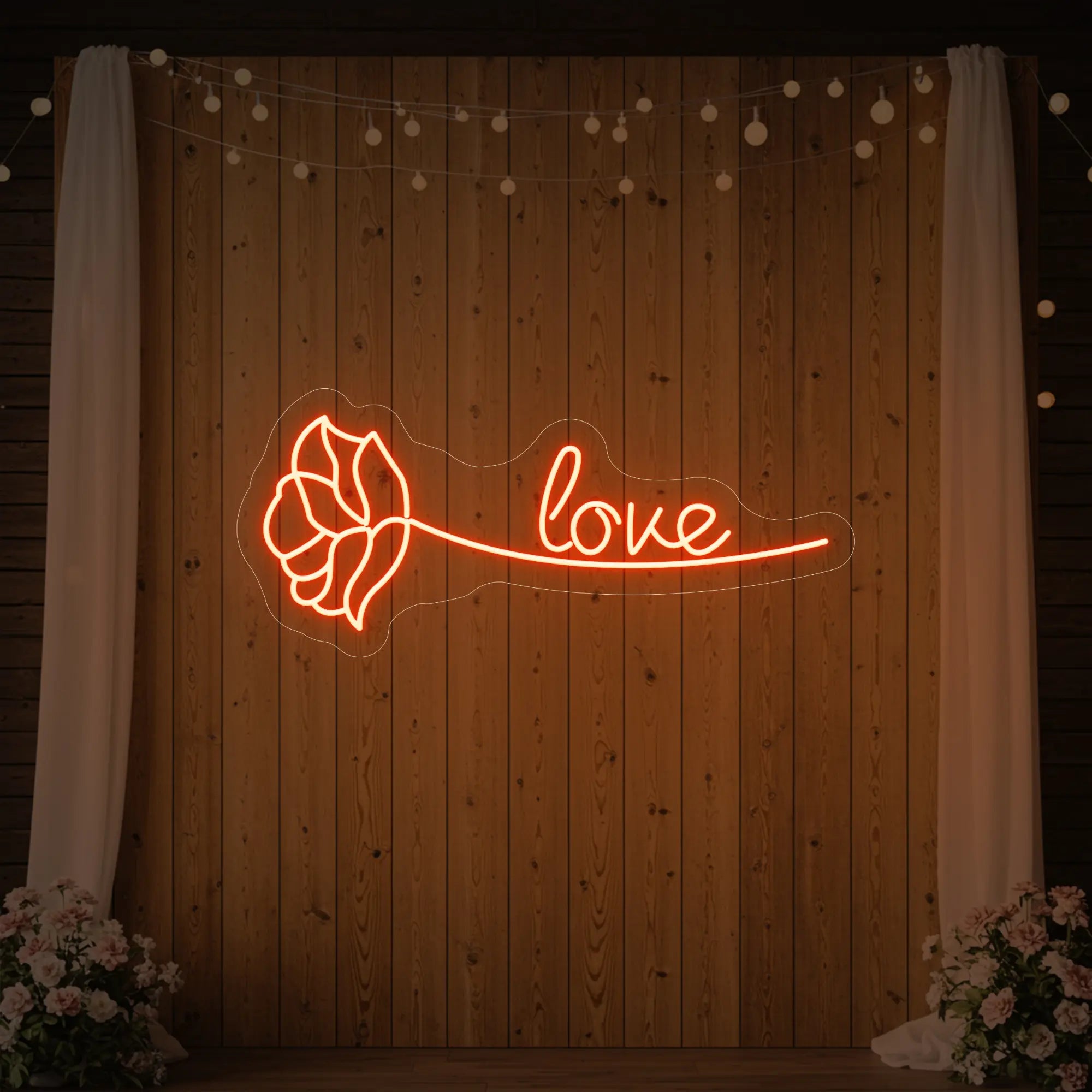 Photo of the 'Just Love Rose' neon sign glowing in golden yellow against a styled interior wall.