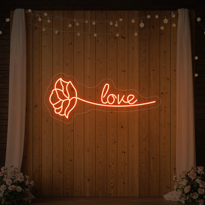 Photo of the 'Just Love Rose' neon sign glowing in golden yellow against a styled interior wall.