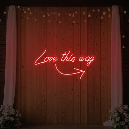 Photo of the 'Love This Way' neon sign glowing in red against a styled interior wall.