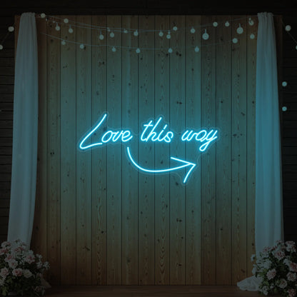 Photo of the 'Love This Way' neon sign glowing in ice blue against a styled interior wall.
